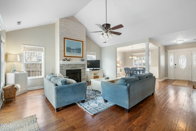 living room with visible vents, high vaulted ceiling, ceiling fan with notable chandelier, hardwood / wood-style flooring, and a fireplace