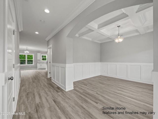 empty room featuring light wood-type flooring, beamed ceiling, coffered ceiling, and crown molding