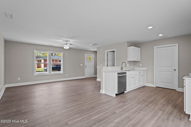 kitchen with stainless steel dishwasher, a peninsula, baseboards, and light countertops