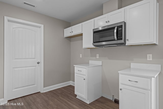 kitchen with dark wood-style flooring, visible vents, light countertops, baseboards, and stainless steel microwave