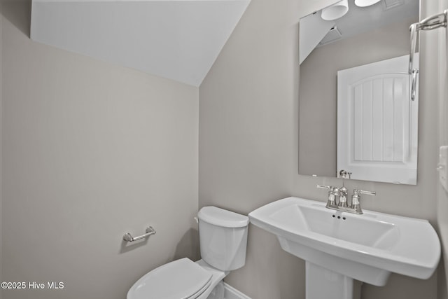 bathroom with baseboards, a sink, lofted ceiling, and toilet
