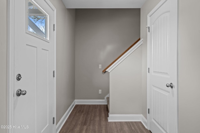 foyer with dark wood-type flooring, baseboards, and stairway