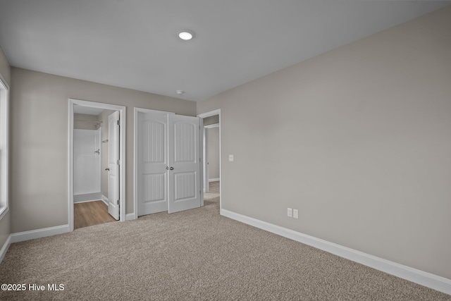 unfurnished bedroom with carpet flooring, baseboards, and ensuite bathroom