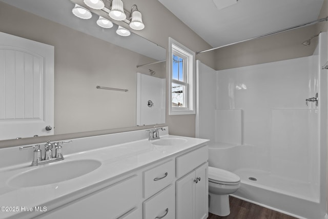 bathroom with wood finished floors, toilet, a sink, and a shower
