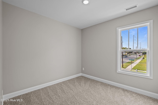 spare room featuring baseboards, visible vents, and carpet