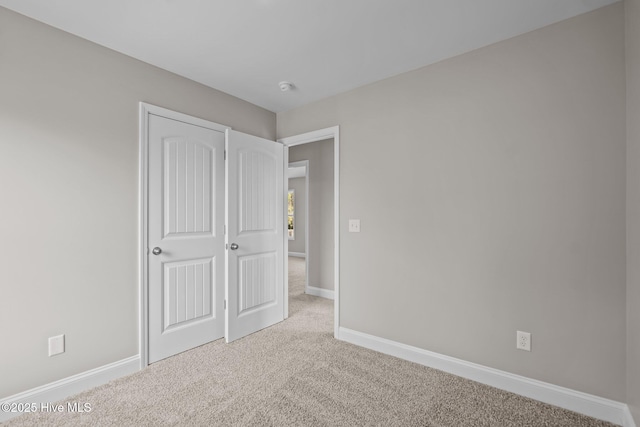 unfurnished bedroom featuring baseboards, carpet, and a closet
