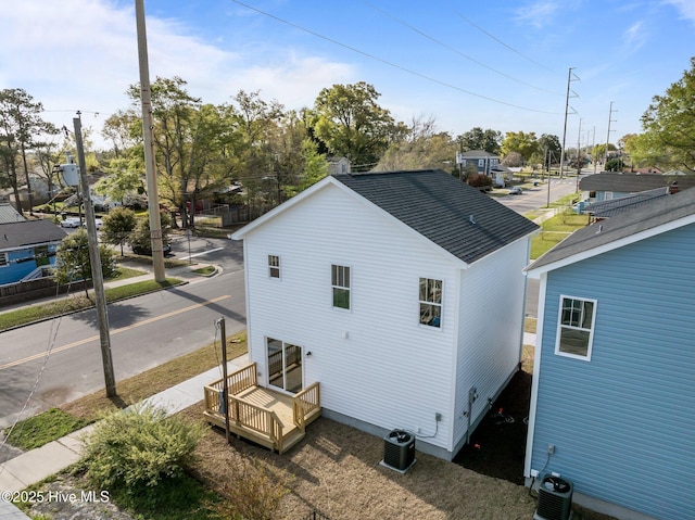view of property exterior with central air condition unit and a shingled roof