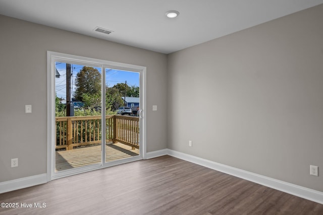 spare room featuring baseboards, wood finished floors, and visible vents