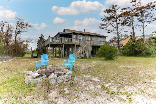 rear view of house featuring an outdoor fire pit, a lawn, and a wooden deck