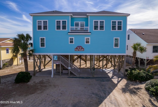 view of front of property with a balcony, driveway, a shingled roof, and a carport