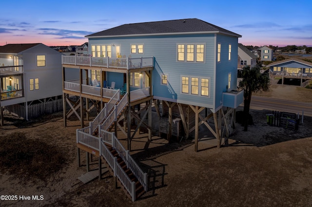 back of property featuring roof with shingles, stairway, and a balcony