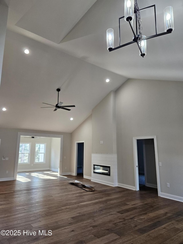 unfurnished living room with dark wood-style floors, baseboards, high vaulted ceiling, and a glass covered fireplace