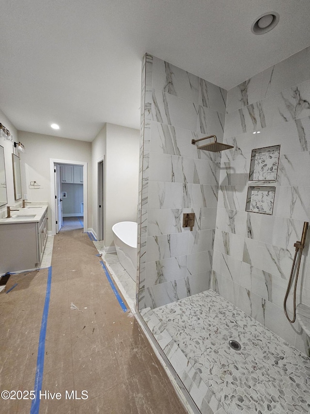 full bathroom featuring baseboards, a tile shower, a freestanding bath, and vanity