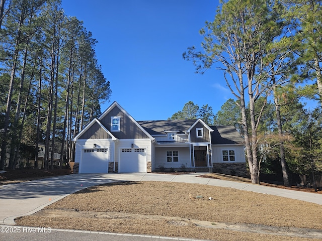 view of front of home with driveway, stone siding, an attached garage, and board and batten siding