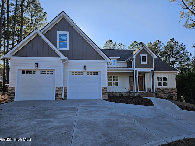 view of front of property featuring a shingled roof, board and batten siding, a standing seam roof, stone siding, and driveway