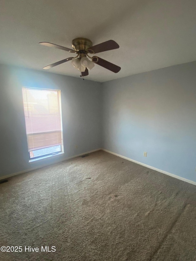 carpeted empty room featuring ceiling fan and baseboards