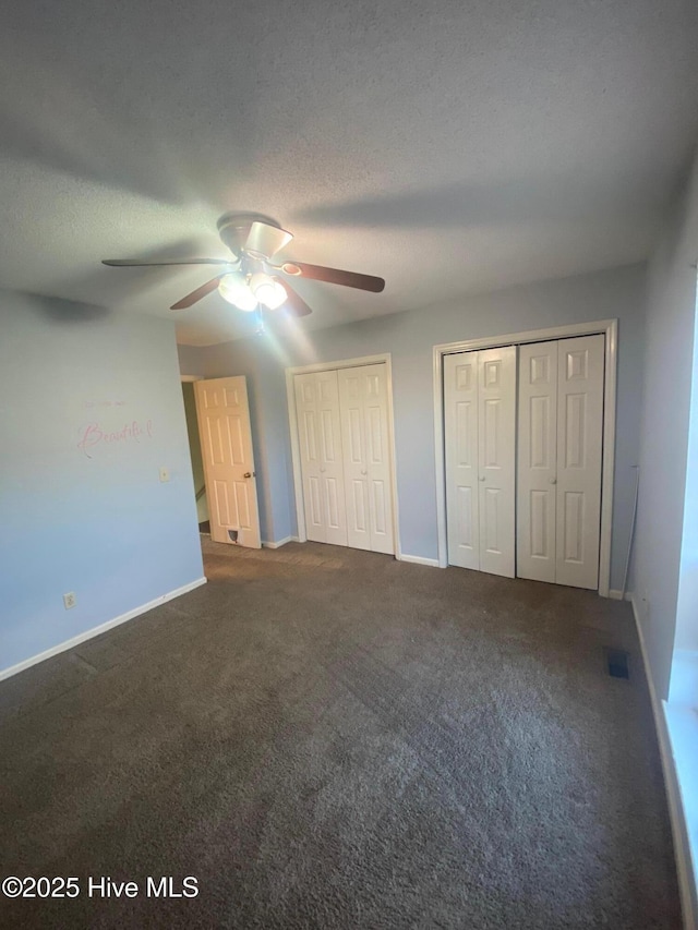 unfurnished bedroom with visible vents, baseboards, a textured ceiling, carpet flooring, and multiple closets