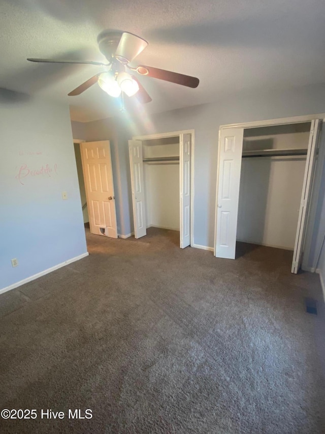 unfurnished bedroom with carpet floors, multiple closets, ceiling fan, a textured ceiling, and baseboards