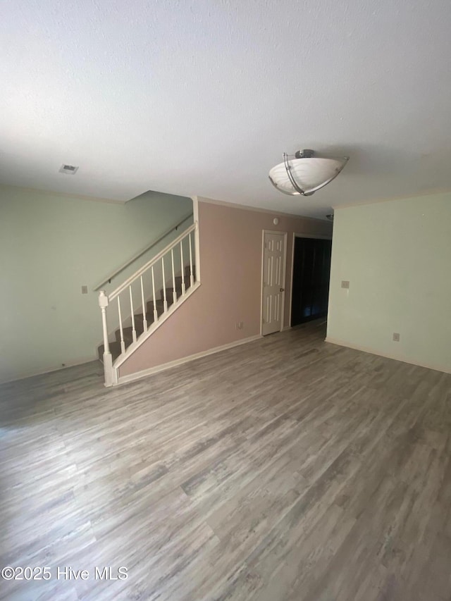 spare room with wood finished floors, visible vents, a textured ceiling, and stairs