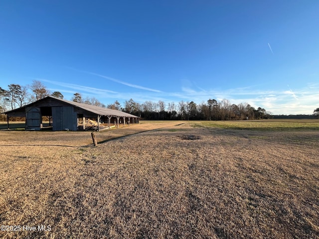 view of yard with a carport, a pole building, a rural view, and an outdoor structure