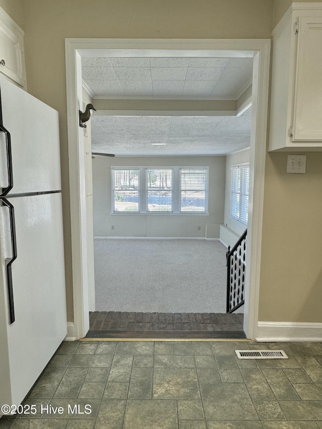 hallway with baseboards, dark colored carpet, visible vents, and a healthy amount of sunlight