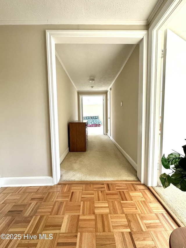 corridor featuring crown molding, a textured ceiling, and baseboards