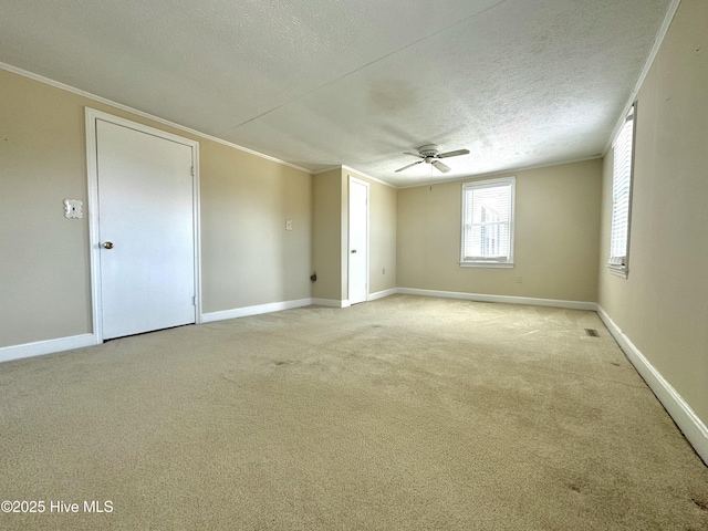 unfurnished room featuring ornamental molding, light colored carpet, a textured ceiling, and baseboards