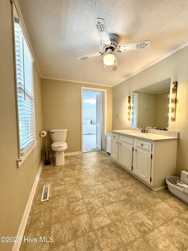 bathroom with ornamental molding, visible vents, ceiling fan, and vanity