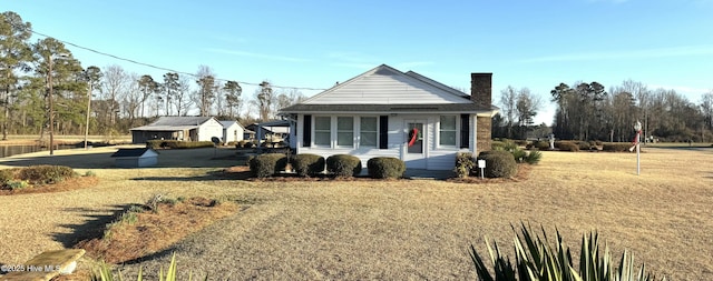 view of front facade featuring a chimney and a front yard