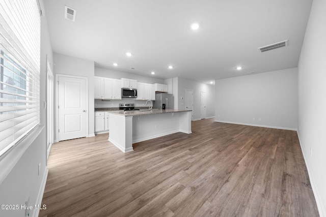 kitchen featuring visible vents, stainless steel appliances, an island with sink, and white cabinetry