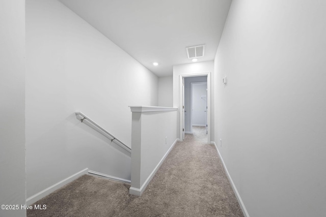 hallway featuring carpet floors, baseboards, and an upstairs landing