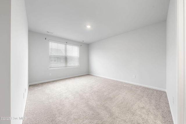 spare room featuring visible vents, baseboards, and light colored carpet