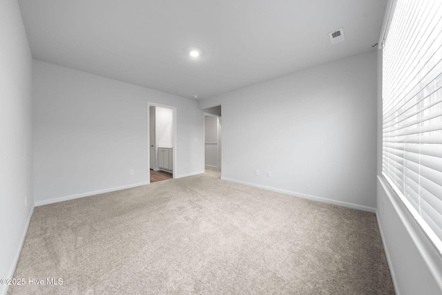 empty room featuring carpet flooring, visible vents, and baseboards