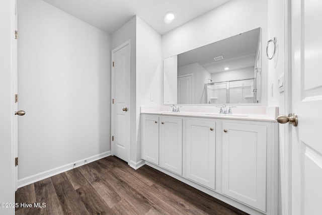 full bathroom featuring wood finished floors, a stall shower, a sink, and baseboards