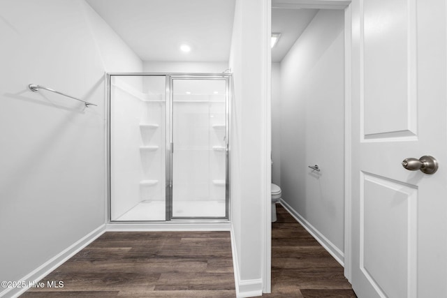 full bath featuring toilet, a shower stall, baseboards, and wood finished floors