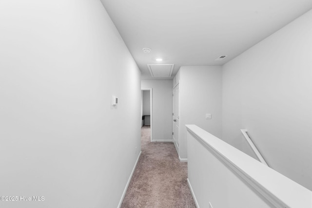 hallway with attic access, baseboards, light colored carpet, and an upstairs landing