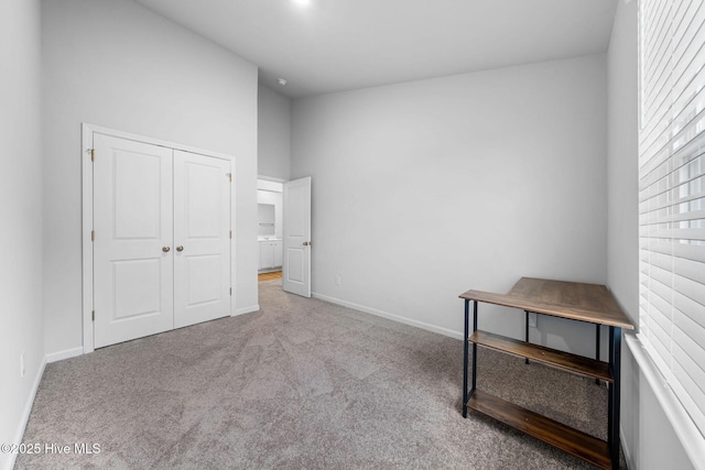 unfurnished bedroom with a closet, light carpet, and baseboards