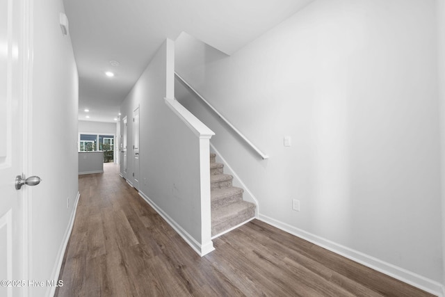 staircase featuring baseboards, wood finished floors, and recessed lighting