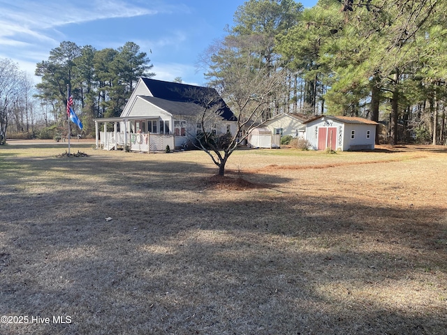 view of property exterior with a shed, covered porch, and a yard