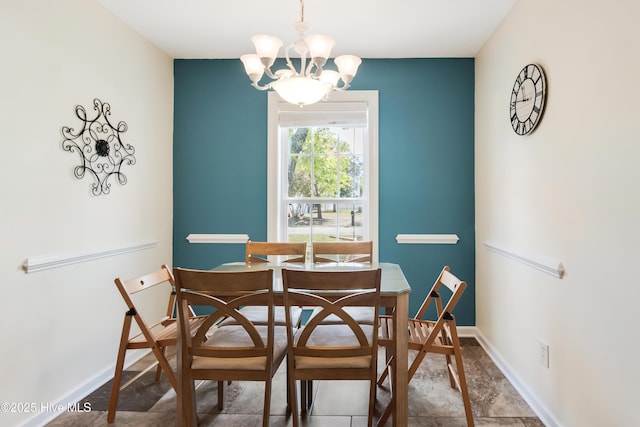 dining space with baseboards and a notable chandelier