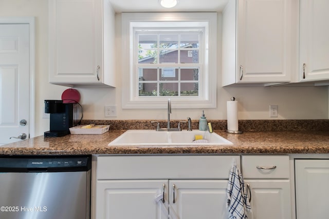 kitchen featuring stainless steel dishwasher, dark countertops, white cabinets, and a sink