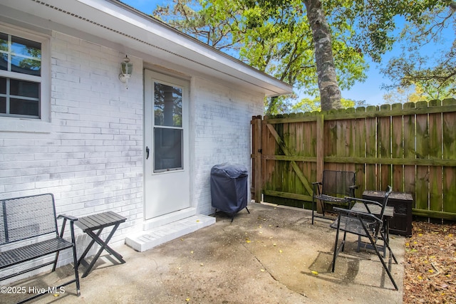 view of patio featuring a gate, fence, and a grill