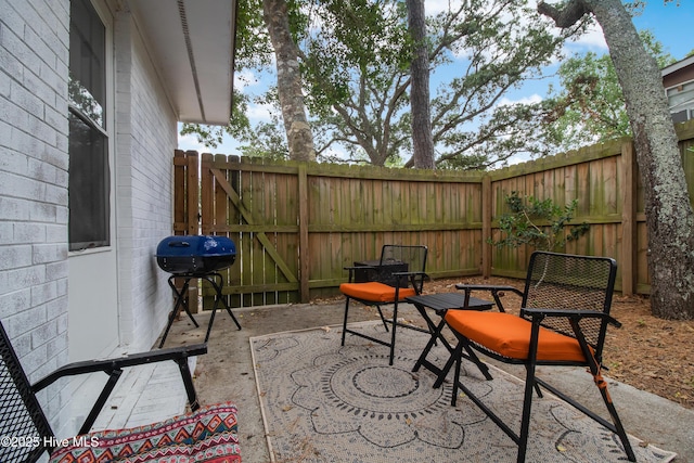 view of patio featuring a grill, a fenced backyard, and a gate