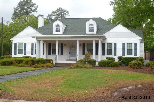 cape cod home featuring a front lawn and a porch