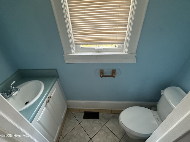 bathroom with toilet, vanity, and tile patterned flooring