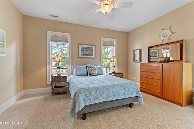 bedroom featuring multiple windows, light colored carpet, baseboards, and a ceiling fan