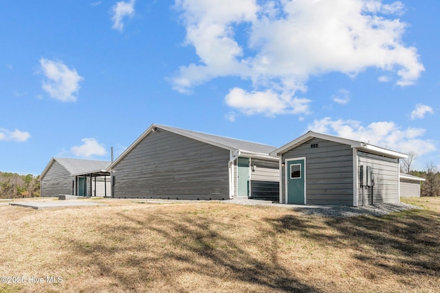 rear view of house with a lawn and an outdoor structure