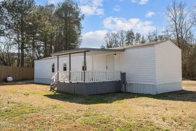 view of front of home featuring fence, a deck, and a front lawn