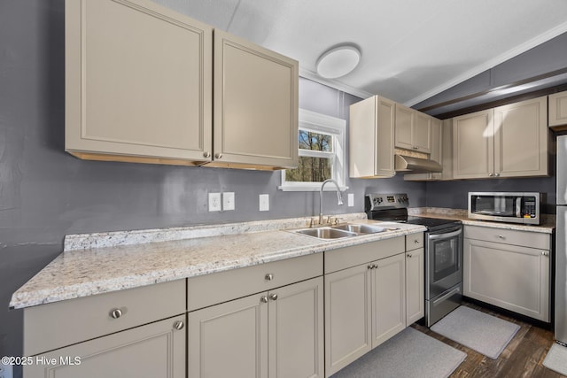 kitchen featuring dark wood-style flooring, stainless steel appliances, under cabinet range hood, a sink, and cream cabinets