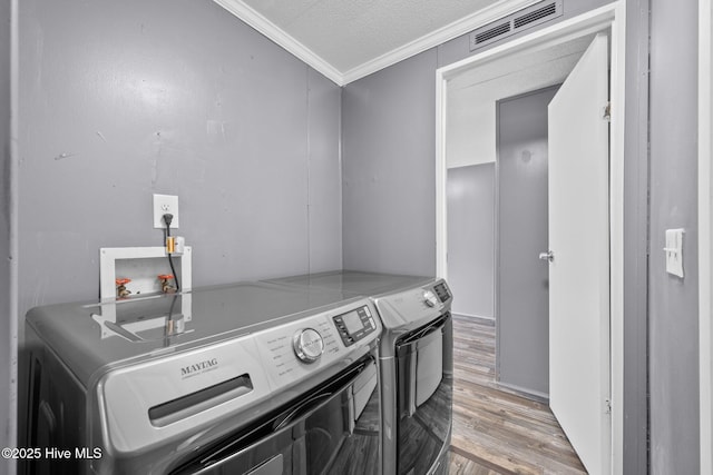 washroom featuring washing machine and dryer, light wood-type flooring, laundry area, visible vents, and ornamental molding